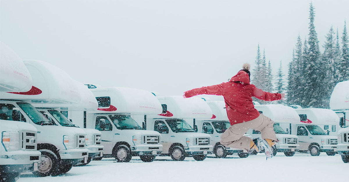 man jumping in the air on snowy rv parking lot